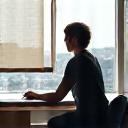 Person doing a gentle desk stretch at a computer.