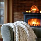 Cozy indoor scene with a warm blanket and a glowing fireplace.